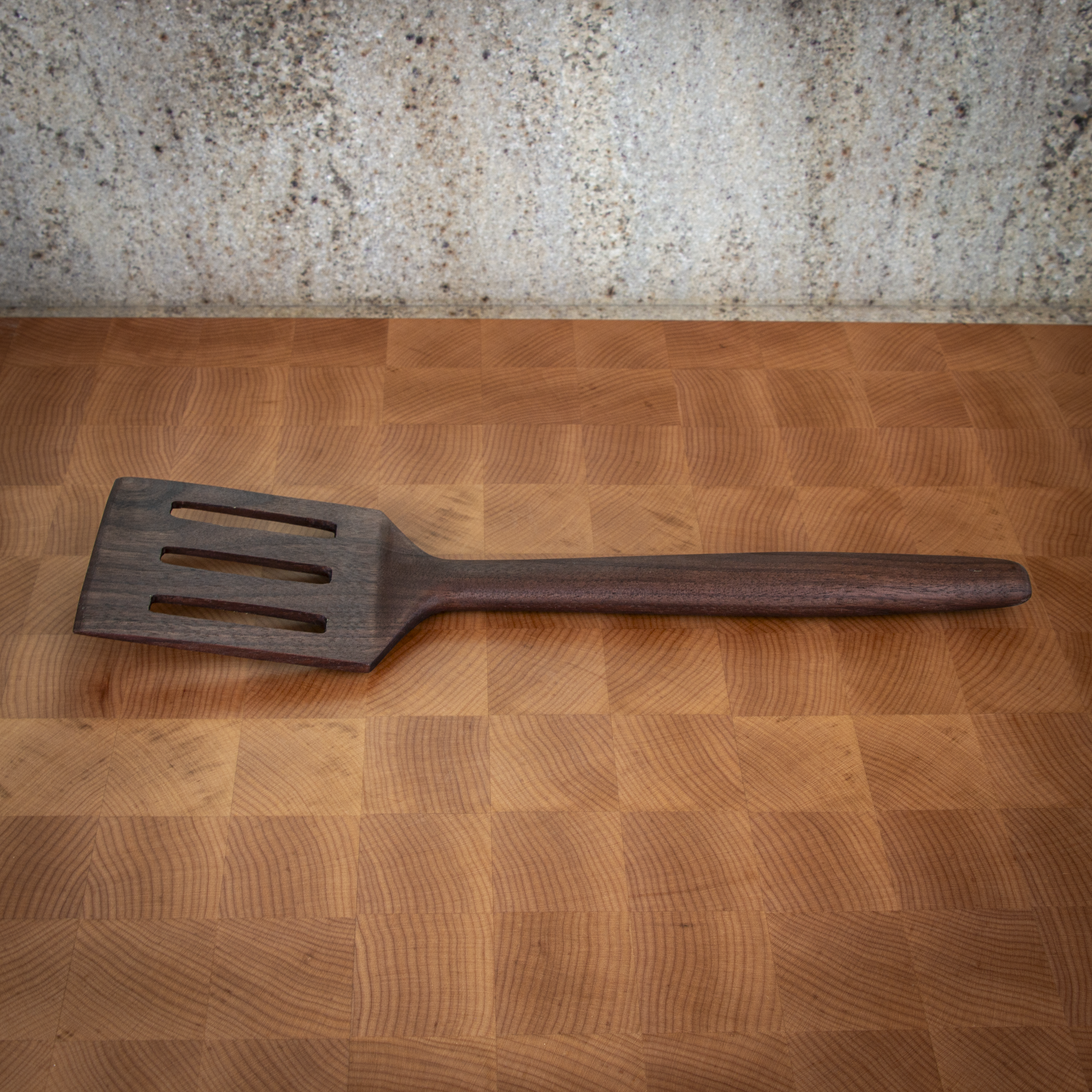 Slotted wood turner spatula for flipping and draining in the kitchen